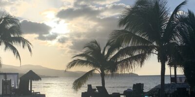 Photo of a beach at sunset with a tiki