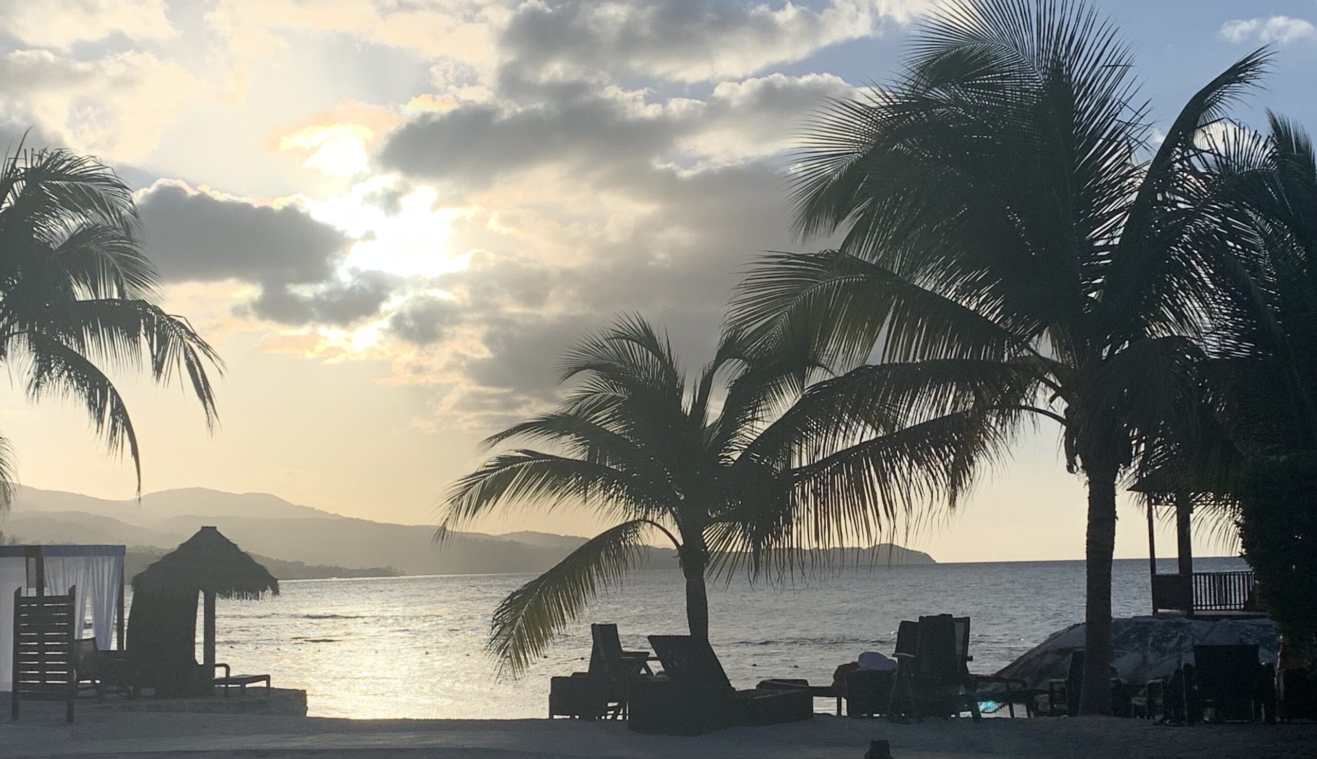 Photo of a beach at sunset with a tiki