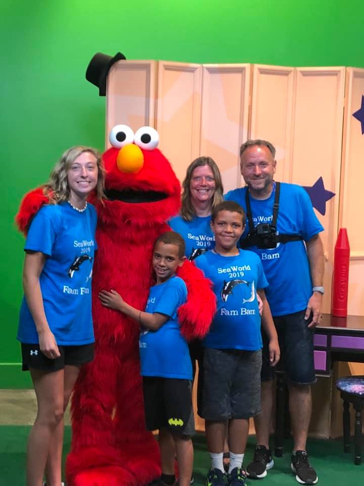 Client testimonial from Laurie and Doug about their vacation to Orlando Theme Park, planned by Mitzi Alexander. Photo of a family smiling with character mascot.