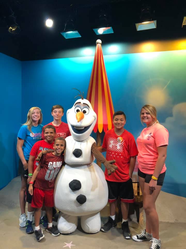 Client testimonial from Laurie and Doug about their vacation to Orlando Theme Park, planned by Mitzi Alexander. Photo of children smiling with a character mascot.