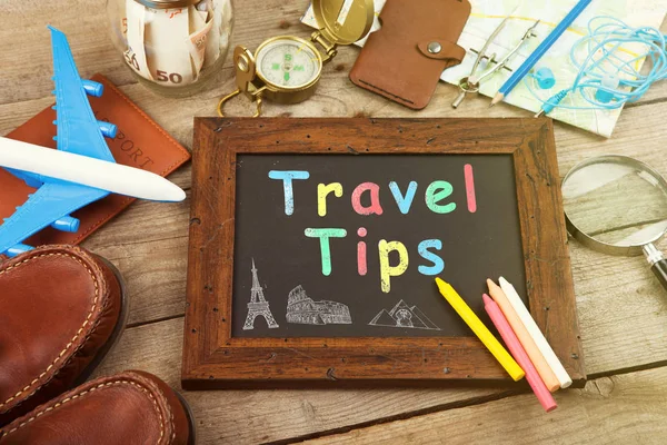 A collection of travel related items surrounding a chalkboard with "Travel Tips" written